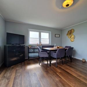 a dining room with a table and chairs and a television at Ferienhaus SeeZeit direkt am Geiseltalsee mit Sauna und Fahrradgarage in Mücheln