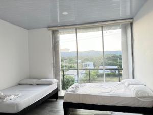 two beds in a room with a large window at Casa quinta Aluna in Carmen de Apicalá +58 photos