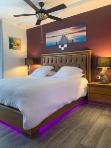 a bedroom with a large bed with a ceiling fan at La grange en pierre - chic & piscine privée in Queyssac