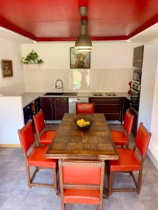 a kitchen with a wooden table and orange chairs at La grange en pierre - chic & piscine privée in Queyssac