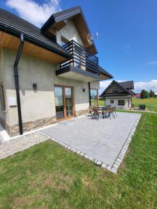 a house with a patio with a table and benches at Domki na Groniku in Nowy Targ