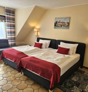 a hotel room with a large bed with red pillows at Haus Scheuten Hotel in Duisburg