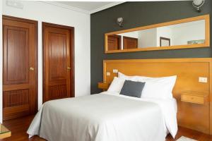 Un dormitorio con una cama blanca y un espejo. en Motel Bambú, en Lugo