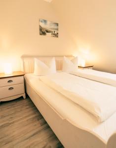 two white beds in a room with two lamps at Haus Seeschwalbe Spiekeroog - Wohnung 12 in Spiekeroog