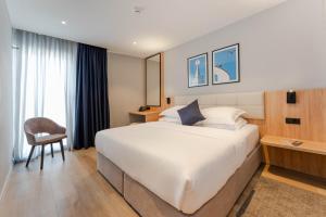 a hotel room with a large bed and a chair at Hotel A'mare in Zadar