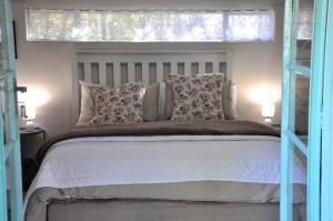 a bedroom with a white bed with a window at The Granadilla in Montagu