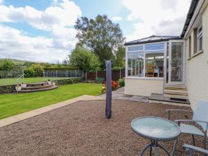 a patio with a table and chairs and a glass house at Craggy View in Kendal