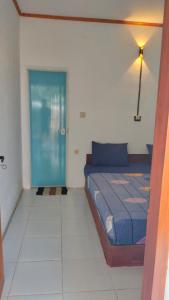 - une chambre avec un lit et une porte bleue dans l'établissement Nadil Homestay, à Kuta Lombok