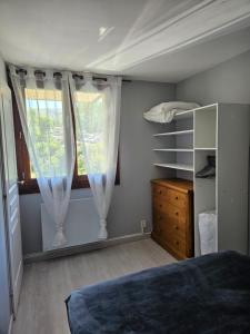 a bedroom with a bed and a dresser and a window at Appartement 1-4 personnes, Résidence "Le Belouga" in Le Mont-Dore