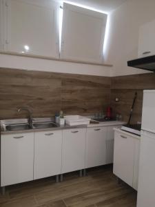 a kitchen with white cabinets and a wooden wall at Terracina Holiday Succursale in Terracina +24 photos