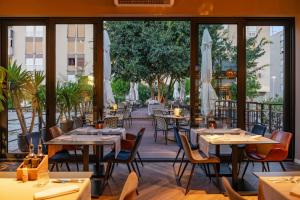 ザダルにあるHotel A'mareのテーブルと椅子、大きな窓のあるレストラン