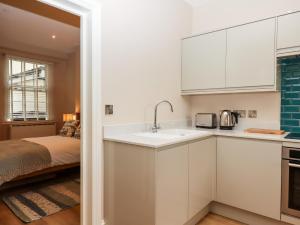 a kitchen with white cabinets and a sink and a bed at 1 Sea Otter House in Teignmouth