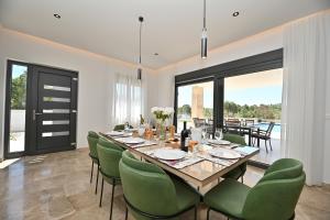 a dining room with a table and green chairs at Villa Donatus in Murvica