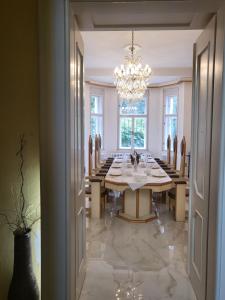 a dining room with a table and a chandelier at Vládní vila in Luhačovice
