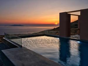 basen bez krawędzi z widokiem na zachód słońca w tle w obiekcie Under the Sun Cycladic Village w mieście Tinos