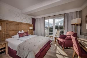 ein Hotelzimmer mit einem Bett und einem Stuhl in der Unterkunft Hotel Bismarck in Bad Hofgastein + 85 Fotos