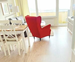 een woonkamer met een rode stoel en een tafel bij Schöne Aussicht in Hohegeiß