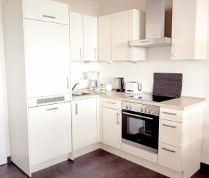 een witte keuken met witte kasten en een fornuis bij Schöne Aussicht in Hohegeiß