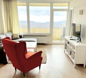 een woonkamer met een rode stoel en een bank bij Schöne Aussicht in Hohegeiß +7 foto's