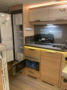 a kitchen with a stove and an open refrigerator at 5 Sterne Wohnwagen all inclusive - direkt auf Messe Hannover - super beheizt - alles vor Ort - Wifi - Fully heated - Mobile Home all inclusive - at Fairground Hanover Trade Fair in Hannover +13 photos