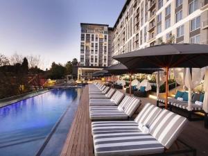 a row of chaise lounges next to a swimming pool at Stunning 1 bedroom apartment in a hotel with pool in Johannesburg