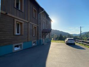 a building with a car parked next to a road at Loft 5 personnes type chalet avec jardin in Saint-Maurice-sur-Moselle