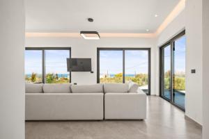 - un salon blanc avec un canapé blanc et des fenêtres dans l'établissement Aetheria & Aura Suites by Temma Villas, à Chersónissos