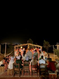 een menigte mensen die 's nachts in stoelen zitten bij Super Luxury camp in Merzouga