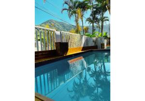 a swimming pool with palm trees and a mountain in the background at Suítes Praia Barequeçaba in São Sebastião