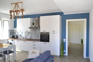 a kitchen with white cabinets and a blue wall at Casa degli Ulivi - Apartment B in Porto San Giorgio