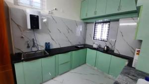 a kitchen with green cabinets and a sink at Hasinihomes 3bhk brand new new service apartment JNTU nizampet pragathi nagar in Hyderabad
