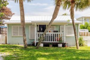 a small green house with palm trees in the yard at Fun-filled home with pool, near beach, pets welcome! in Panama City Beach