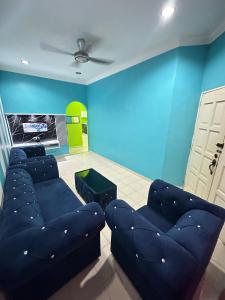 a living room with couches and a blue wall at Homestay Pusat Bandar Kangar in Kangar