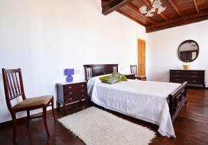 a bedroom with a bed and a chair and a mirror at GALIHOST - A Casa de Rosa in Ribadumia