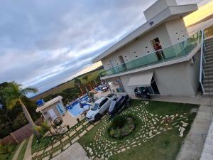 a house with a car parked in front of it at Chácara Arena JK com Piscina integrada com Sauna e Hidromassagem in Ibiúna
