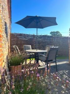a table and chairs with an umbrella on a patio at Shergar in Kelling +11 photos