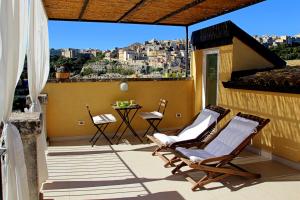 een patio met 2 stoelen en een tafel op een balkon bij TrinaSicula Ragusa Ibla in Ragusa