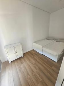 ein weißes Zimmer mit einem Bett und einem kleinen Schrank in der Unterkunft Casa da leira in Madalena
