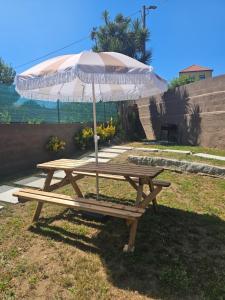 ein Picknicktisch mit einem Sonnenschirm auf dem Rasen in der Unterkunft Casa da leira in Madalena + 9 Fotos