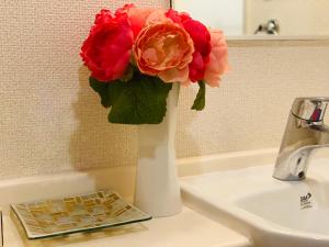 a vase with flowers sitting on a bathroom sink at Shinjuku House in Tokyo
