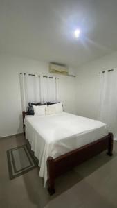 Un dormitorio con una cama con sábanas y almohadas blancas. en La Castillada House, en Santa Cruz de Barahona