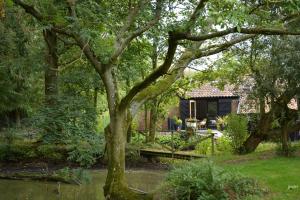 a cottage in the garden with a tree at Milk Parlour in Spexhall