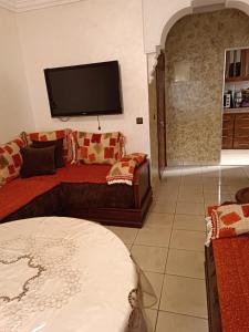 a living room with a couch and a flat screen tv at Très belle Appart à louer pour vos vacances-Dyafa Agadir- A 2chambres in Agadir