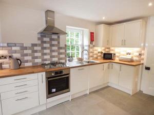 a kitchen with white cabinets and a stove top oven at Beaver Grove Cottage in Betws-y-coed