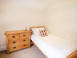a bedroom with two twin beds and a wooden dresser at Beaver Grove Cottage in Betws-y-coed
