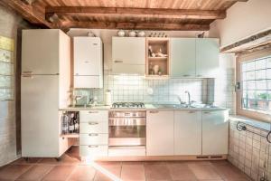 a kitchen with white cabinets and a refrigerator at Abissinia, Gioiello nel Bosco in Poiano