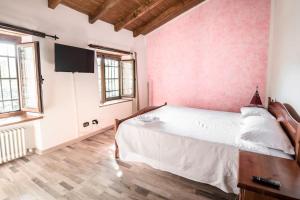 1 dormitorio con cama blanca y paredes rosas en Abissinia, Gioiello nel Bosco, en Poiano