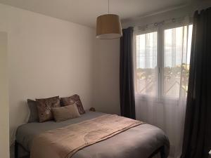 a bedroom with a bed and a large window at Le nid douillet à 500m de la gare in Évreux