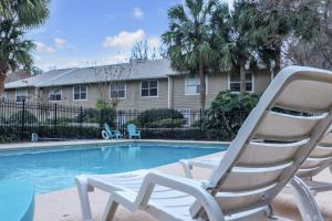 a white chair sitting next to a swimming pool at Blissful Haven - Updated & Fully Equipped Condo in Gainesville