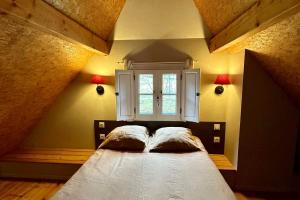 1 cama con 2 almohadas en una habitación con ventana en Les chalets d'Arrens, en Arrens-Marsous